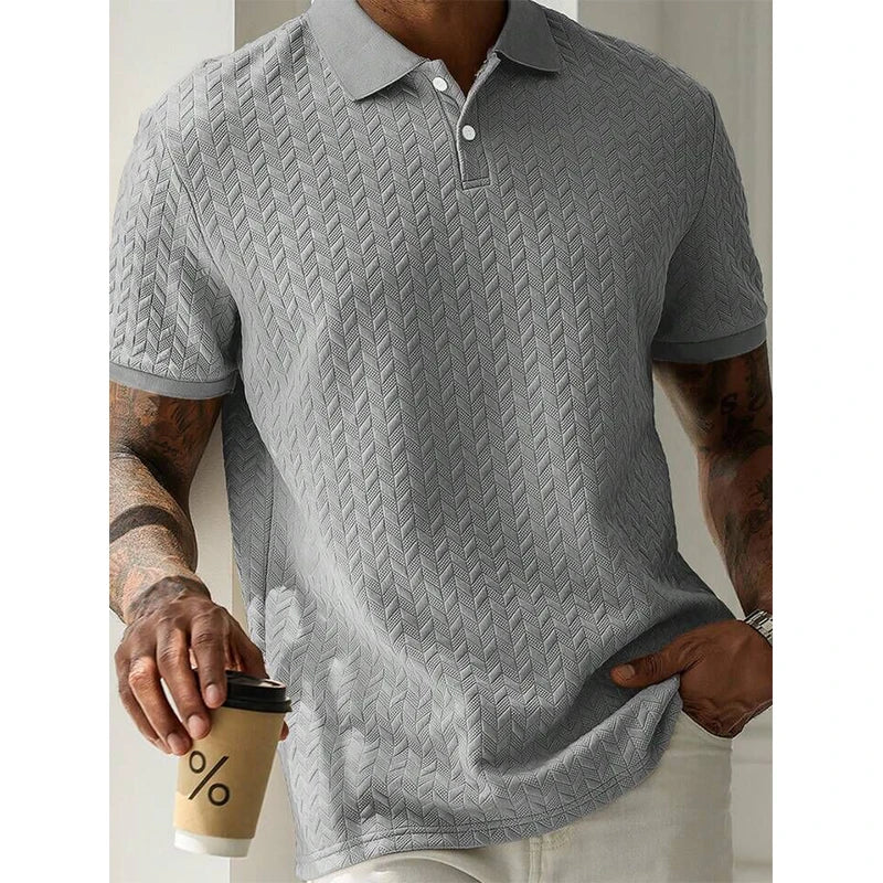 Gray textured polo shirt with geometric pattern, worn with white pants, holding coffee cup