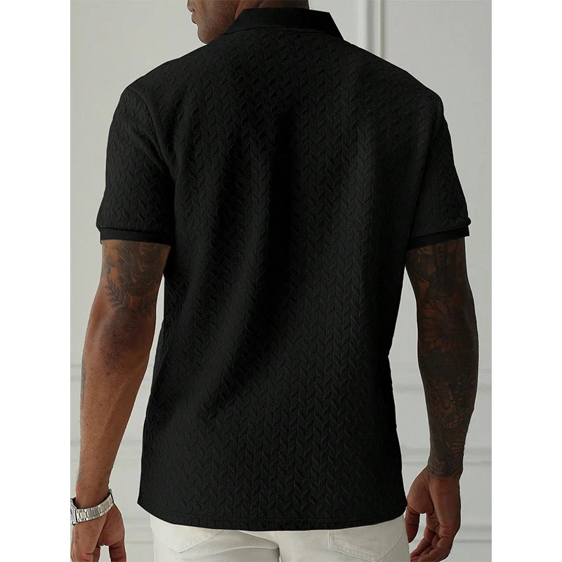 Black textured polo shirt with herringbone pattern, worn by man with tattoos, paired with white pants