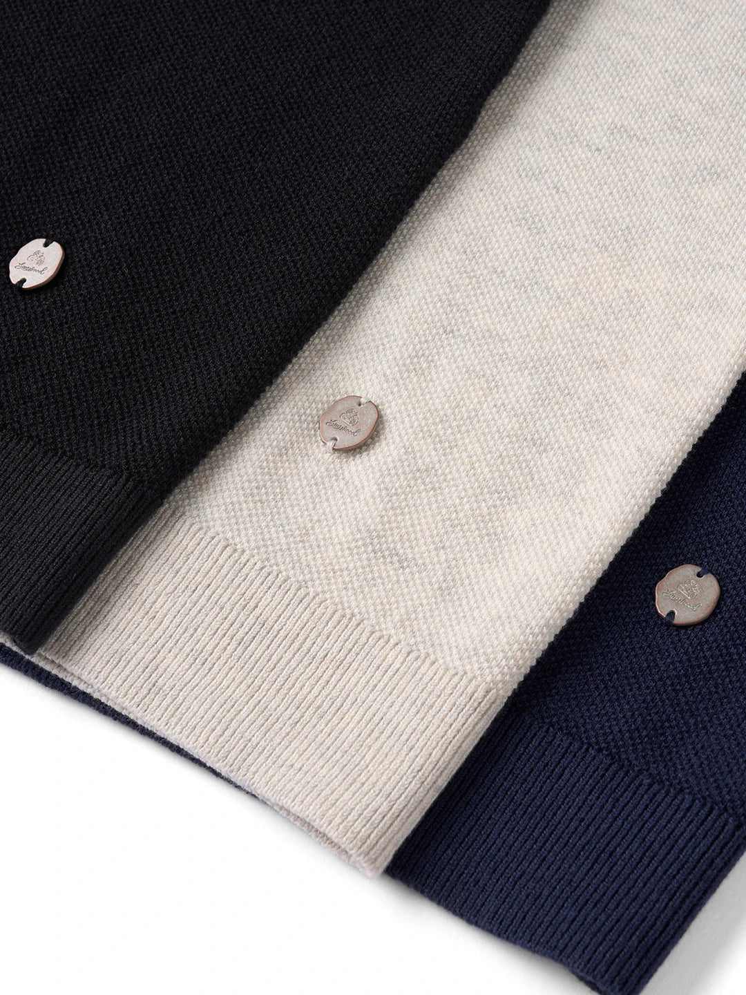 Black, cream, and navy knit cardigans with textured ribbed hems and branded buttons