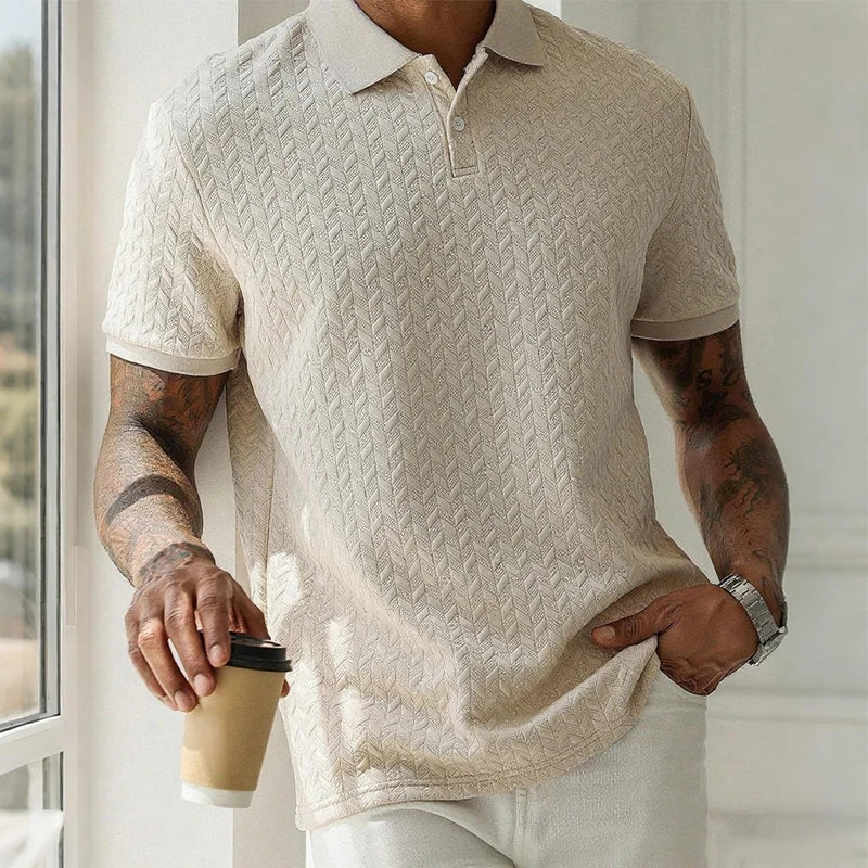 Man wearing textured beige polo shirt with herringbone pattern, holding coffee cup near window